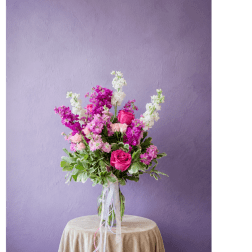 Pink and white flower arrangement in a clear glass vase on a draped table