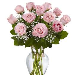 Bouquet of light pink roses with white filler flowers in a clear glass vase