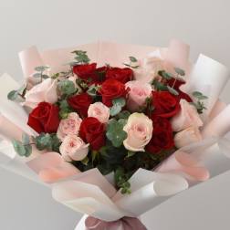 Bouquet of red and pale pink roses wrapped in white paper