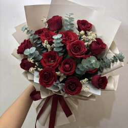Bouquet of red roses with eucalyptus and cream filler, wrapped in beige paper