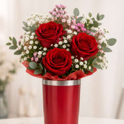 Red roses with pink and white filler flowers in a red vase