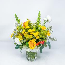 Yellow and white mixed flower arrangement in a clear glass vase