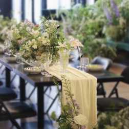 Pastel floral centerpiece on a table with a pale draped runner