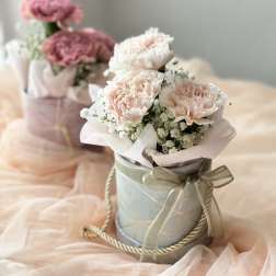 Pink carnations in a ribbon-tied gift box with baby's breath