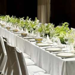 Long banquet table with white floral centerpieces and place settings
