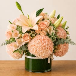 Peach bouquet with lilies, roses, and hydrangeas in a glass vase