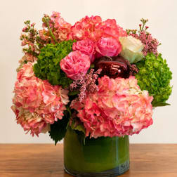Pink hydrangeas and roses arranged in a green glass vase