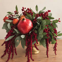 Pomegranate and berry arrangement in a gold vase