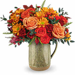 Bouquet of orange and red flowers in a rustic ceramic pitcher