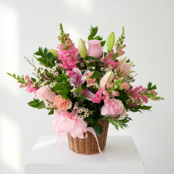 Pink floral basket arrangement with roses, lilies, and snapdragons