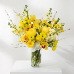 Yellow mixed flower arrangement in a clear glass vase
