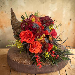 Orange roses and burgundy mums arranged in a rustic basket.