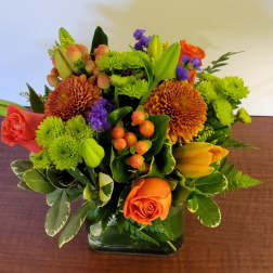 Orange roses and green chrysanthemums in a square glass vase