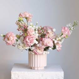 Pink and white flowers arranged in a ribbed blush vase