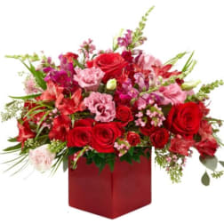 Red and pink mixed flower arrangement in a red box