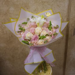 Bouquet of pink and white roses wrapped in pale paper with a pink ribbon