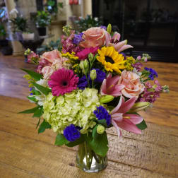 Mixed bouquet in a clear glass vase with roses, lilies, hydrangea, and gerbera daisies