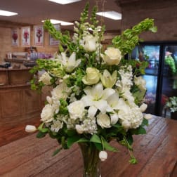 White floral arrangement in a glass vase with roses and lilies