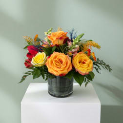 Colorful rose arrangement in a glass vase on a white pedestal