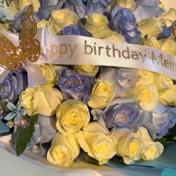Bouquet of pale yellow and blue roses with a birthday ribbon