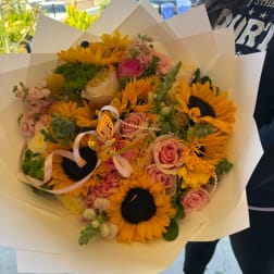 Bouquet of sunflowers and pink roses wrapped in white paper