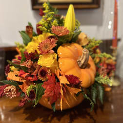 Autumn floral arrangement in a pumpkin with yellow, orange, and red blooms