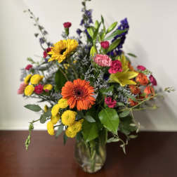 Mixed bouquet in a glass vase with sunflowers, gerbera daisies, and colorful blooms