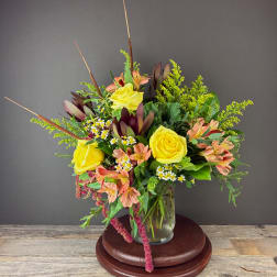 Mixed bouquet in a glass vase with yellow roses and peach flowers