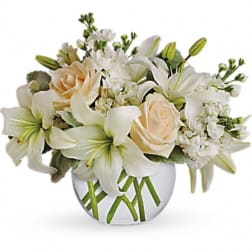 White lilies and pale roses arranged in a clear glass vase