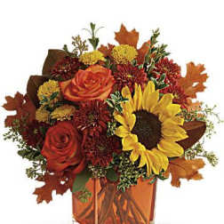 Autumn bouquet with sunflowers and orange roses in a square glass vase