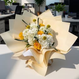Bouquet of white hydrangeas and yellow roses wrapped in cream paper