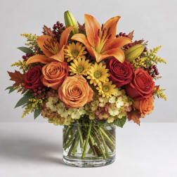 Orange lilies and roses in a glass vase with yellow flowers