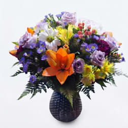 Mixed bouquet of colorful flowers in a dark textured vase