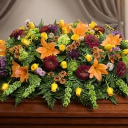 Colorful floral casket spray with orange lilies and yellow blooms