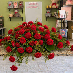 Large red dahlia arrangement on a counter with greenery