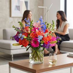 Colorful mixed bouquet in a clear glass vase on a coffee table