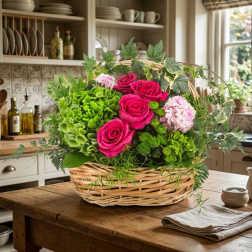 Basket arrangement of pink roses and green hydrangeas with ivy
