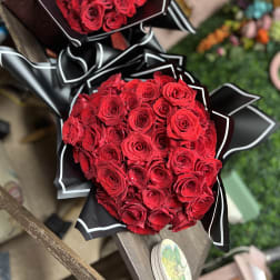 Two bouquets of red roses wrapped in black paper with white trim
