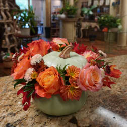 Floral arrangement around a pale green pumpkin-shaped container