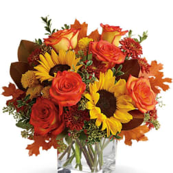 Bouquet of orange roses and sunflowers in a clear square vase