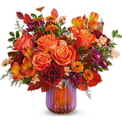 Orange roses and mixed autumn flowers in a striped glass vase