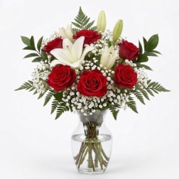 Red roses and white lilies arranged in a clear glass vase