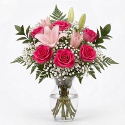 Pink roses and lilies arranged in a clear glass vase