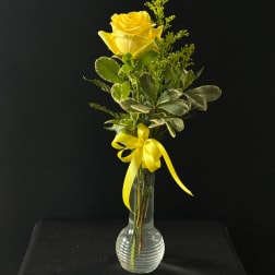 Yellow rose in a clear glass vase with a yellow ribbon
