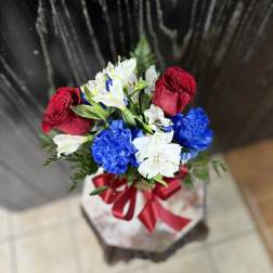 Bouquet of red roses, white alstroemeria, and blue carnations tied with a red ribbon