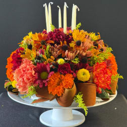 Colorful floral centerpiece with candles on a white pedestal stand