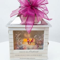 Decorative white lantern with a large pink bow and cardinal artwork