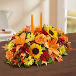 Autumn floral centerpiece with orange candles and mixed blooms on a table