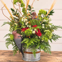 Mixed floral arrangement in a metal bucket with bird decorations