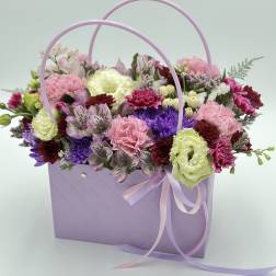 Lavender gift bag filled with pink, purple, and white flowers